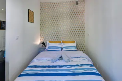 a bedroom with a bed with blue and white stripes at - Luxury Appart Climatisé Plage - in Cannes