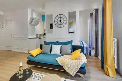 a living room with a blue couch and a kitchen at - Luxury Appart Climatisé Plage - in Cannes