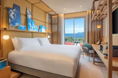 a hotel room with a bed and a desk and a window at Canopy by Hilton Cannes in Cannes