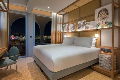 a bedroom with a bed and a desk and a window at Canopy by Hilton Cannes in Cannes