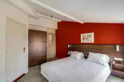a bedroom with a white bed with a red wall at Hotel Le Mistral in Cannes