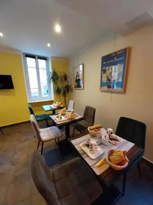 a dining room with two tables and chairs and yellow walls at Hotel Le Mistral in Cannes