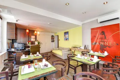 a restaurant with tables and chairs in a room at Hotel Le Mistral in Cannes