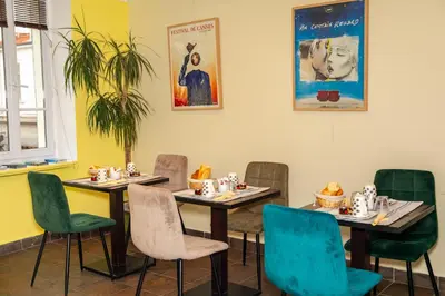 a dining room with tables and chairs and a poster at Hotel Le Mistral in Cannes