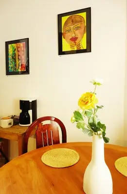 a wooden table with a vase with a yellow flower on it at CANNES - À DEUX PAS DU PALAIS DES FESTIVALS in Cannes