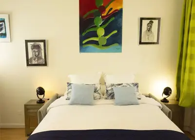 a bedroom with a large white bed with pictures on the wall at CANNES - À DEUX PAS DU PALAIS DES FESTIVALS in Cannes