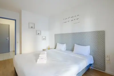 a white bed with two towels on top of it at Residhotel Villa Maupassant in Cannes