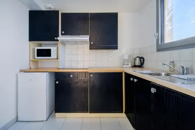 a kitchen with black cabinets and a sink and a microwave at Residhotel Villa Maupassant in Cannes