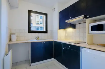 a kitchen with blue cabinets and a microwave at Residhotel Villa Maupassant in Cannes