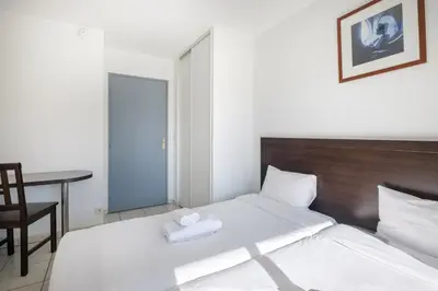 a bedroom with a bed and a chair and a table at Residhotel Cannes Festival in Cannes