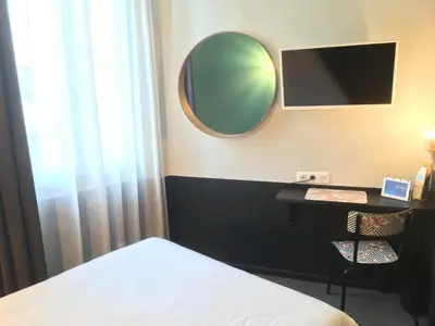 a bedroom with a bed and a mirror and a table at Hotel Alnea in Cannes