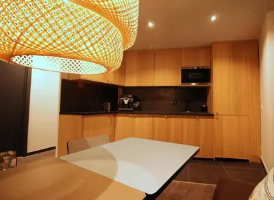 a kitchen with wooden cabinets and a table and a chandelier at Hotel Alnea in Cannes