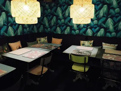 two tables and chairs in a room with wallpaper at Hotel Alnea in Cannes