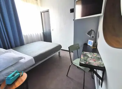 a hotel room with a bed and a table and a chair at Hotel Alnea in Cannes