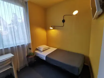 a small bedroom with a bed and a window at Hotel Alnea in Cannes