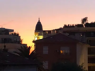 a view of a building with a clock tower at sunset at Émeraude Croisette in Cannes