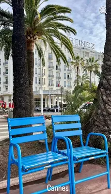 two blue benches next to palm trees and a building at Émeraude Croisette in Cannes