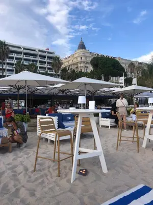 a table and chairs on a beach with umbrellas at Émeraude Croisette in Cannes