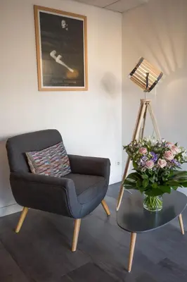 a living room with a chair and a table with a vase of flowers at Hotel Abrial by Soniho in Cannes