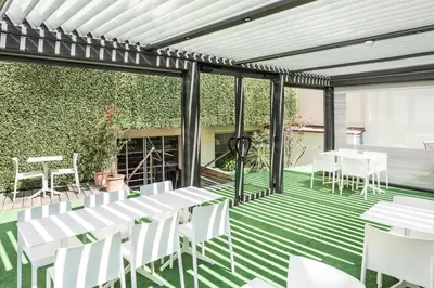 a patio with white tables and chairs on a green floor at Hotel Abrial by Soniho in Cannes
