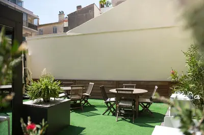 a patio with a table and chairs on the grass at Hotel Abrial by Soniho in Cannes