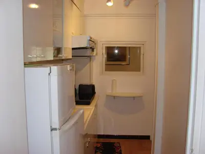 a kitchen with a white refrigerator and a table at Good location flat in Cannes