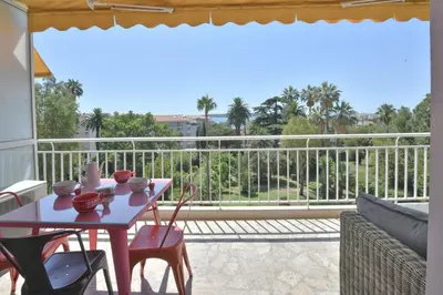 a patio with a table and chairs on a balcony at 1-Br Apartment Sea View Steps from Beaches in Cannes
