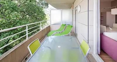 a balcony with a glass table and green chairs at Arthur Properties Bel Air in Cannes