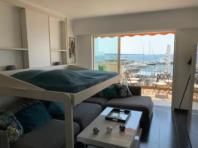 a bedroom with a bed and a couch and a large window at O Festival Palace, terrace with panoramic sea view in Cannes