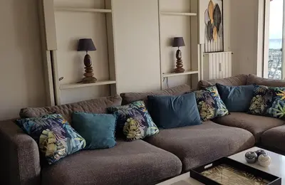 a living room with a brown couch with blue pillows at O Festival Palace, terrace with panoramic sea view in Cannes