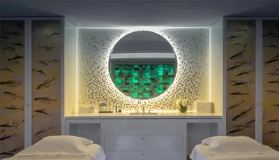 a bathroom with a mirror on a wall with two beds at Hôtel Martinez, in The Unbound Collection by Hyatt in Cannes