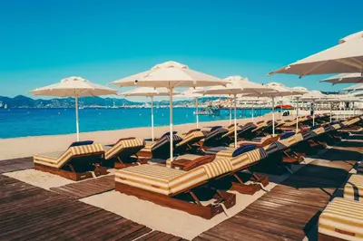 a bunch of lounge chairs and umbrellas on a beach at Hôtel Martinez, in The Unbound Collection by Hyatt in Cannes