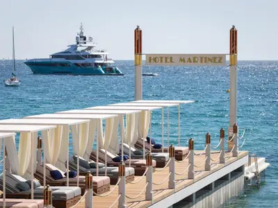a dock with chairs and a boat in the water at Hôtel Martinez, in The Unbound Collection by Hyatt in Cannes