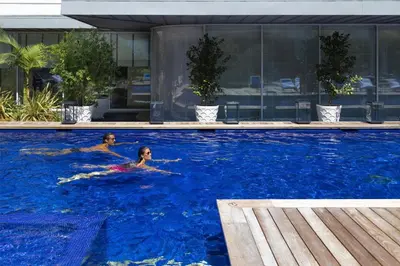 two people swimming in a large swimming pool at Hôtel Martinez, in The Unbound Collection by Hyatt in Cannes