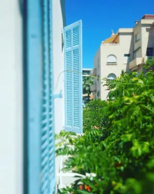 a window with blue shutters on a building at Hotel Alexandre III in Cannes