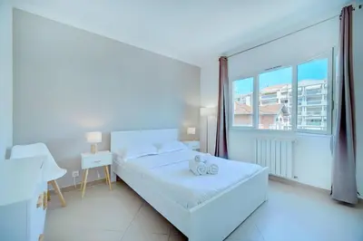a white bedroom with a bed and a large window at IMMOGROOM - Terrace - 2 bedrooms - Downtown - Air conditioning - Wifi in Cannes