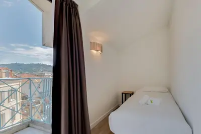 a small room with a bed and a balcony at Residhotel Les Coralynes in Cannes