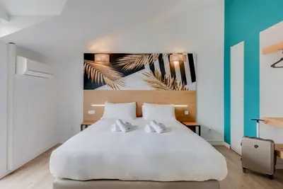 a bedroom with a large white bed with two pillows at Residhotel Les Coralynes in Cannes