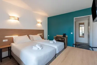 a hotel room with two beds and a desk at Residhotel Les Coralynes in Cannes