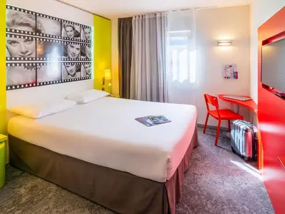 a hotel room with two beds and a desk at ibis Styles Cannes Le Cannet in Cannes
