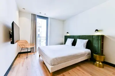a bedroom with a large bed and a chair at Florella Croisette Apartment in Cannes