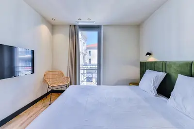 a bedroom with a large bed and a window at Florella Croisette Apartment in Cannes