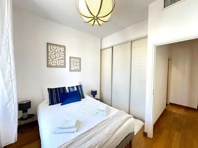 a bedroom with a large white bed with blue pillows at 3 bedrooms with sea view - 4 min Palais & beaches in Cannes