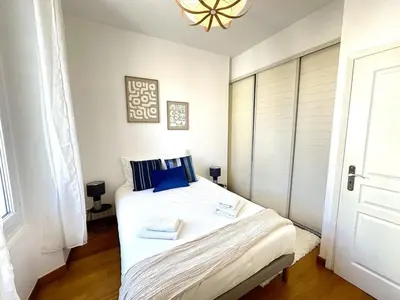 a bedroom with a large white bed with blue pillows at 3 bedrooms with sea view - 4 min Palais & beaches in Cannes