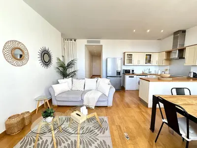 a living room with a white couch and a kitchen at 3 bedrooms with sea view - 4 min Palais & beaches in Cannes