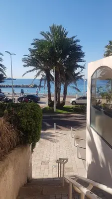 a sidewalk with a table and palm trees on the beach at CLEM SOLEIL in Cannes