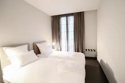 two beds in a hotel room with white sheets at Residence Bivouac in Cannes