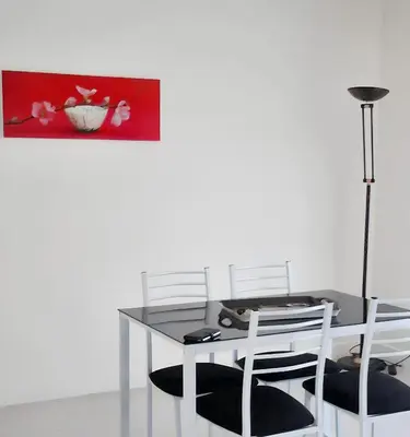 a dining room table with two white chairs and a painting at Appartement charmant avec vue sur la mer au Cannet - 58 m² in Le Cannet