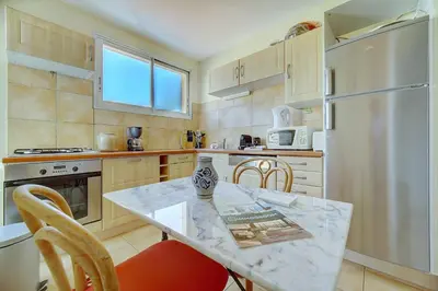 a kitchen with a table and chairs and a refrigerator at IMMOGROOM - Terrace- Parking - Quiet place - CONGRESSBEACHES in Cannes