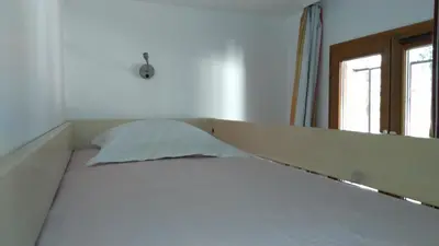 an empty bed in a room with a window at Studio cabine vue mer, piscine panoramique, parking couvert in Cannes
